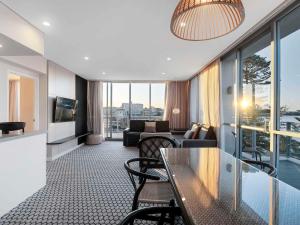 a living room with a table and chairs and a couch at Peppers Manly Beach in Sydney