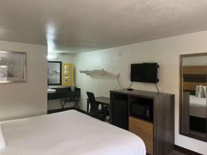 ein Hotelzimmer mit einem Bett und einem Schreibtisch mit einem TV in der Unterkunft Motel 6 Cross Lanes, WV Goff Mountain Rd in Cross Lanes