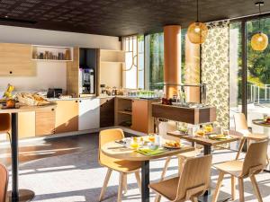 een keuken en eetkamer met tafels en stoelen bij Mercure Agen Centre in Agen