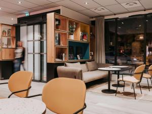 - un salon avec un canapé, des tables et des chaises dans l'établissement ibis Rouen Centre Rive Droite Pasteur, à Rouen