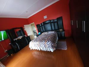 a bedroom with a bed and red walls at Dumi Place in Mataffin