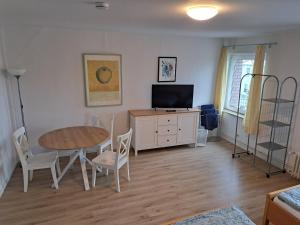 ein Wohnzimmer mit einem Tisch und einem TV in der Unterkunft Zimmervermietung Hartl in Barmstedt