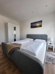 a large bed in a bedroom with white walls at Apartment Nia mit Sauna und Whirlpool in Euskirchen
