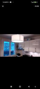 a kitchen with white cabinets and a light fixture at Calme et écologie aux portes de Paris in Ivry-sur-Seine