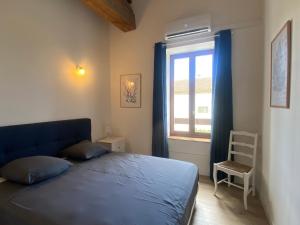 a bedroom with a blue bed and a window at T3 bord canal du midi, piscine in Homps +10 photos