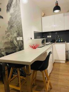 a kitchen with a table with two chairs and a microwave at Au calme de la Gaité in Saint-Jacques-de-la-Lande