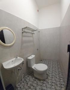 a bathroom with a toilet and a sink and a mirror at Dehills Hotel Luwuk in Luwuk