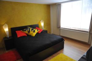 a bedroom with a black bed with colorful pillows on it at Apartment Home Frit Home in Brussels