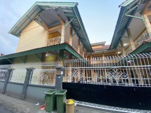 une maison avec une clôture et deux poubelles devant elle dans l'établissement OYO Life 93265 Kos Cendana Seruni Raya, à Mataram