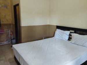 a bedroom with a bed with white sheets and pillows at OYO Life 93265 Kos Cendana Seruni Raya in Mataram