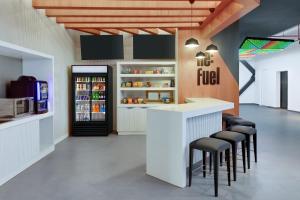 a restaurant with a counter with stools and a refrigerator at Aloft Santo Domingo Piantini in Santo Domingo