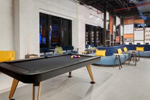 a pool table in a room with couches at Aloft Santo Domingo Piantini in Santo Domingo