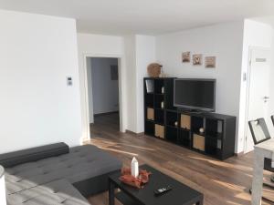Fewo Rhein-Lahn Penthouse OG3-1 في لانشتاين: غرفة معيشة مع أريكة وتلفزيون بشاشة مسطحة