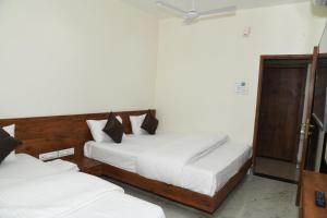 a bedroom with two beds and a sliding glass door at Hotel Apex, Akkalkot in Akalkot