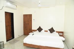 a bedroom with a bed with white sheets and black pillows at Hotel Apex, Akkalkot in Akalkot