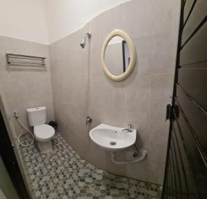 a bathroom with a toilet and a sink and a mirror at Dehills Hotel Luwuk in Luwuk