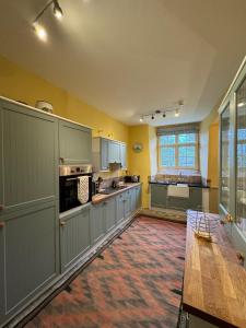 a large kitchen with green cabinets and a table at Braithwaite Hall Apartment in East Witton