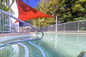 黃金海岸的住宿－Freshly Renovated Modern Waterfront 1 Bedroom unit，围栏旁的游泳池,带红旗