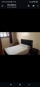 a bedroom with a white bed with a black headboard at Appartement meublé in Meknès