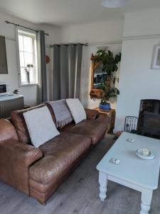 sala de estar con sofá marrón y mesa en The garden apartment en St Ives