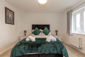 una camera da letto con un grande letto verde con due cuscini di Spacious Modern House with Free Parking 