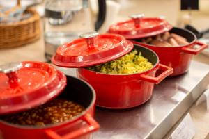4 vasi rossi pieni di cibo su un bancone di Kalvin House Budapest a Budapest