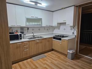 a kitchen with white cabinets and a sink and a microwave at Byungjeom-yeok 2 Stay 