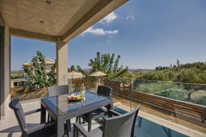 a patio with a table and chairs on a balcony at Azor Luxury Villa I in Mouzákion