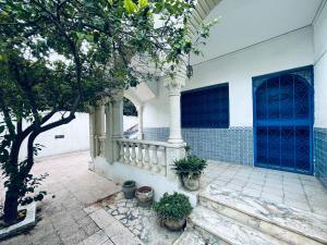Villa le bon coin de la marsa في المرسى: منزل به باب أزرق ونباتات الفخار