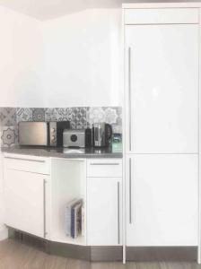 a kitchen with white cabinets and a microwave at New City Centre Apartment in Nottingham in Nottingham