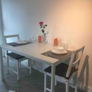 uma mesa branca com duas cadeiras e um vaso com uma flor em New City Centre Apartment in Nottingham em Nottingham