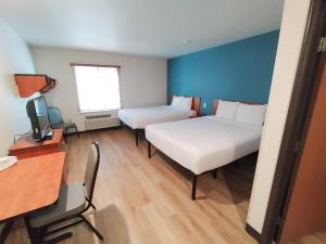 a room with two beds and a desk and a television at WoodSpring Suites Asheville in Asheville