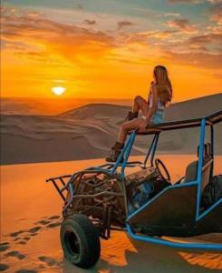a woman sitting on the top of a vehicle in the desert at Merzouga Luxury Camp in Merzouga