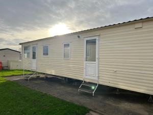a white trailer with two chairs parked next to it at Coastal Caravan Holidays - Goldfinch 22 in Withernsea