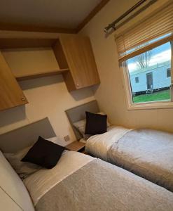 威瑟恩西的住宿－Coastal Caravan Holidays - Goldfinch 22，带窗户的客房内的两张床