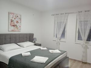 a white bedroom with a bed with towels on it at Apartmani Marija in Vrdnik