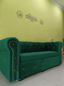 a green couch in a room with stickers on the wall at IRDINA HOMESTAY forMuslims - Changlun in Changlun