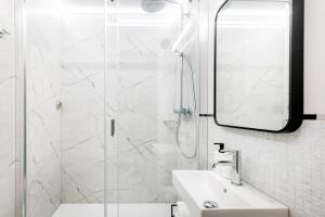 ein weißes Bad mit einer Dusche und einem Waschbecken in der Unterkunft LIKE LAKES UKIEL PARK 40 parking FV in Olsztyn