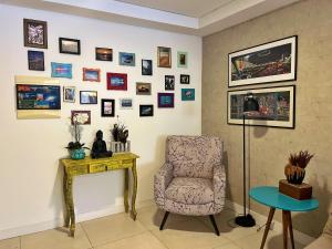 a room with a chair and a table and pictures on the wall at Garden Novo Campeche - apartamento com jardim privativo, bem próximo à praia in Florianópolis