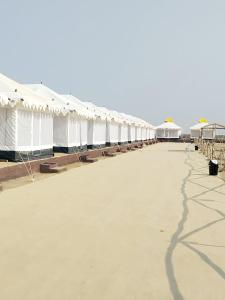 een lange rij witte tenten met tafels en parasols bij Rann Heritage Resort in Dhordo