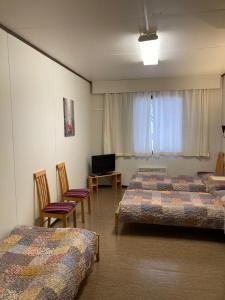 a room with two beds and chairs and a television at Budget apartment in Kotka # 1 in Kotka