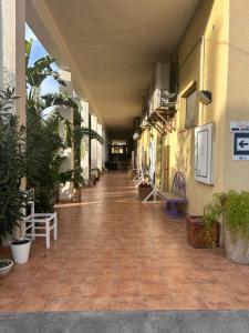 un couloir vide d'un bâtiment avec des plantes en pot dans l'établissement Beteyà Hostel Don Bosco, à Catane