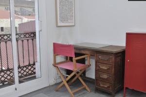- un bureau avec une chaise rose à côté d'un balcon dans l'établissement Beautiful & Bright Apartment Near Ramblas, à Barcelone