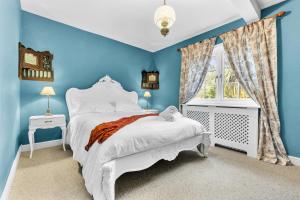 Un dormitorio azul con una cama blanca y una ventana en Reigate Gem en Redhill