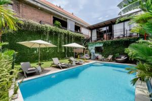 een zwembad met stoelen en parasols naast een gebouw bij Big Brother Berawa Beach in Canggu