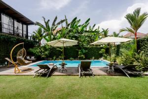a pool with chairs and tables and umbrellas at Big Brother Berawa Beach in Canggu