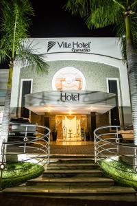 a hotel entrance with stairs and palm trees at Ville Hotel Gramadão in Votuporanga
