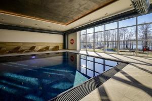 a swimming pool in a building with chairs and windows at Resort Orsino in Horní Planá