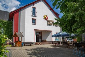 ein rot-weißes Gebäude mit Tischen und Stühlen in der Unterkunft Hotel Zum Stern Spreewald in Werben