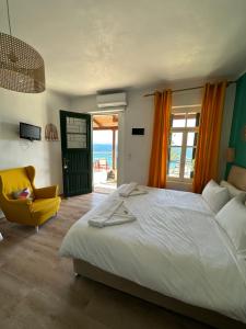 a bedroom with a large bed and a yellow chair at Akteon Rooms in Agia Galini